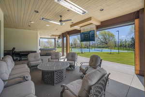 View of patio with a tennis court, a hot tub, outdoor lounge area, and fence