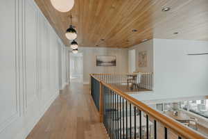 Hallway featuring baseboards, wooden ceiling, an upstairs landing, light wood-type flooring, and recessed lighting