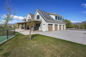 View of front of property featuring concrete driveway, a mountain view, fence, and a front lawn