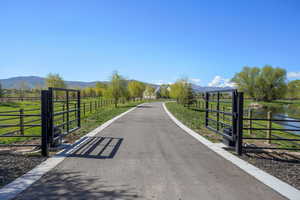 View of entry with a water and mountain view, a rural view, a gated entry, and driveway