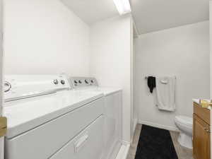 Laundry room with laundry area, light tile patterned floors, baseboards, and washing machine and clothes dryer