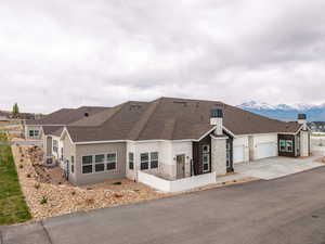 Ranch-style home featuring stone siding, stucco siding, driveway, a shingled roof, and an attached garage