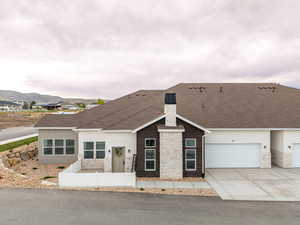 Ranch-style house featuring stone siding, a chimney, driveway, and stucco siding