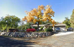 Ranch-style house featuring driveway and fence