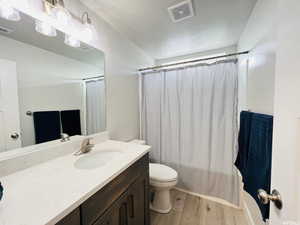 Full bathroom featuring toilet, vanity, wood finished floors, and visible vents