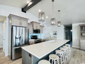 Kitchen featuring appliances with stainless steel finishes, pendant lighting, a sink, and a spacious island