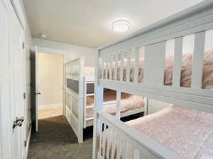 Bedroom with dark colored carpet and a textured ceiling