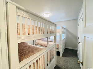 Interior space featuring baseboards, dark colored carpet, and a textured ceiling