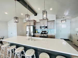 Kitchen with lofted ceiling with beams, a kitchen breakfast bar, stainless steel appliances, pendant lighting, and a sink