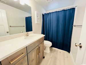 Bathroom with toilet, visible vents, wood finished floors, and vanity