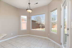 Unfurnished dining area featuring baseboards, visible vents, and a wealth of natural light