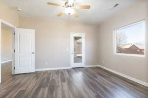 Unfurnished room with a ceiling fan, dark wood finished floors, visible vents, and baseboards