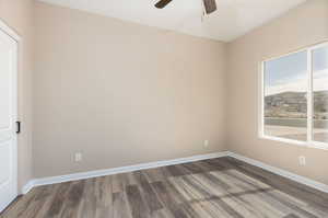 Empty room featuring ceiling fan, wood finished floors, and baseboards