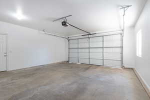 Garage featuring a garage door opener and baseboards