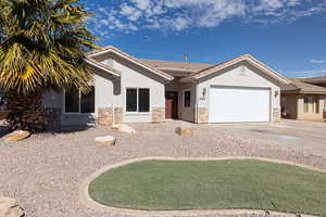 Single story home featuring an attached garage, stone siding, a tiled roof, and stucco siding