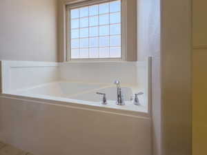 Bathroom featuring a garden tub and a textured wall