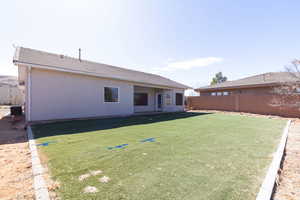 Back of house with a yard, fence, and stucco siding