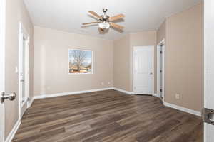 Unfurnished bedroom with dark wood-style floors, ceiling fan, baseboards, and a textured ceiling