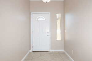 Foyer with light tile patterned floors and baseboards