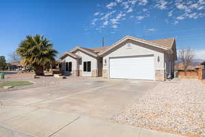 View of front of property with stone siding, an attached garage, a tiled roof, and stucco siding