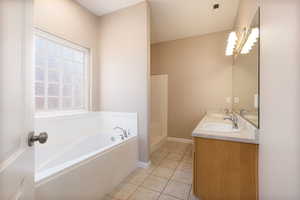 Bathroom featuring a garden tub, visible vents, a sink, and tile patterned floors