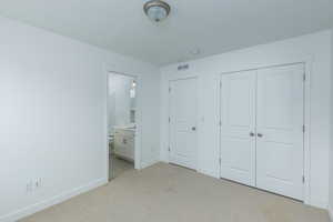 Unfurnished bedroom with a closet, visible vents, light carpet, a textured ceiling, and baseboards