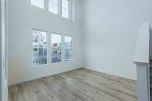Empty room featuring plenty of natural light, light wood-style flooring, and baseboards