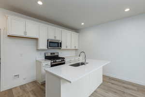 Kitchen with white cabinets, a kitchen island with sink, stainless steel appliances, and a sink