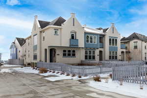 View of front facade with fence and stucco siding