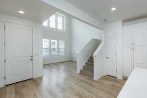 Foyer entrance with stairs, light wood finished floors, visible vents, and recessed lighting