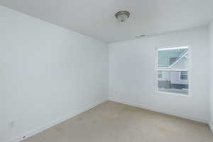 Spare room with baseboards, a textured ceiling, visible vents, and light colored carpet