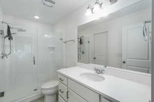 Bathroom with toilet, a stall shower, visible vents, and vanity
