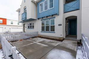 Snow covered property entrance featuring fence and stucco siding