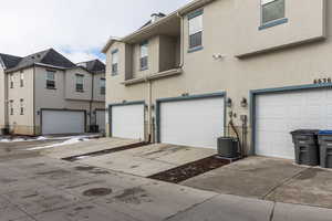 View of front facade featuring central air condition unit, an attached garage, and stucco siding