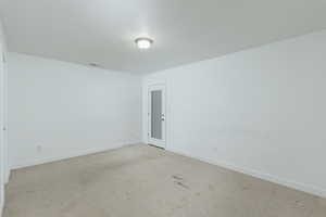 Spare room featuring visible vents, light carpet, baseboards, and a textured ceiling