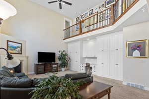 Living room featuring a lit fireplace, built in desk, visible vents, and light colored carpet