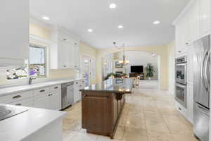 Kitchen featuring stainless steel appliances, arched walkways, white cabinets, and a kitchen island