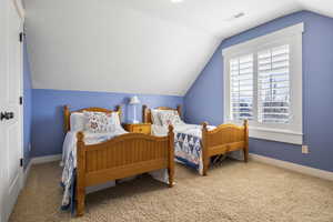 Bedroom featuring lofted ceiling, carpet, visible vents, and baseboards