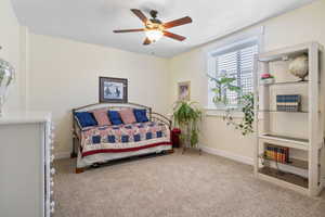 Carpeted bedroom featuring ceiling fan and baseboards