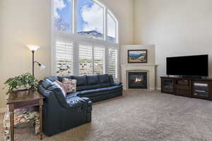 Carpeted living room with a tile fireplace, baseboards, and a high ceiling