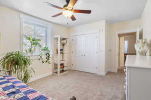 Interior space with a ceiling fan, a closet, light carpet, and baseboards