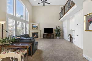 Living area with a fireplace with flush hearth, a high ceiling, baseboards, and light colored carpet