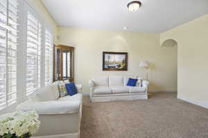 Carpeted living area featuring arched walkways and baseboards