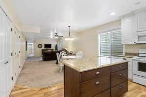 Kitchen with a center island, pendant lighting, open floor plan, white cabinets, and white appliances