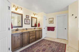 Full bathroom featuring tile patterned flooring, a sink, baseboards, and double vanity