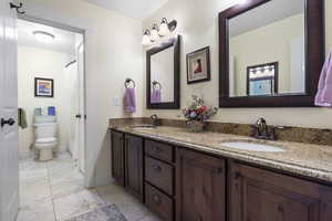 Bathroom with double vanity, baseboards, toilet, and a sink