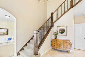 Staircase featuring baseboards, a high ceiling, and tile patterned floors