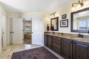 Bathroom featuring double vanity, tile patterned flooring, a sink, and ensuite bathroom