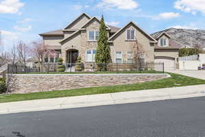 View of front of house featuring driveway, stone siding, a fenced front yard, and stucco siding