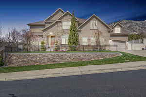 View of front of house featuring a fenced front yard, stucco siding, an attached garage, stone siding, and driveway